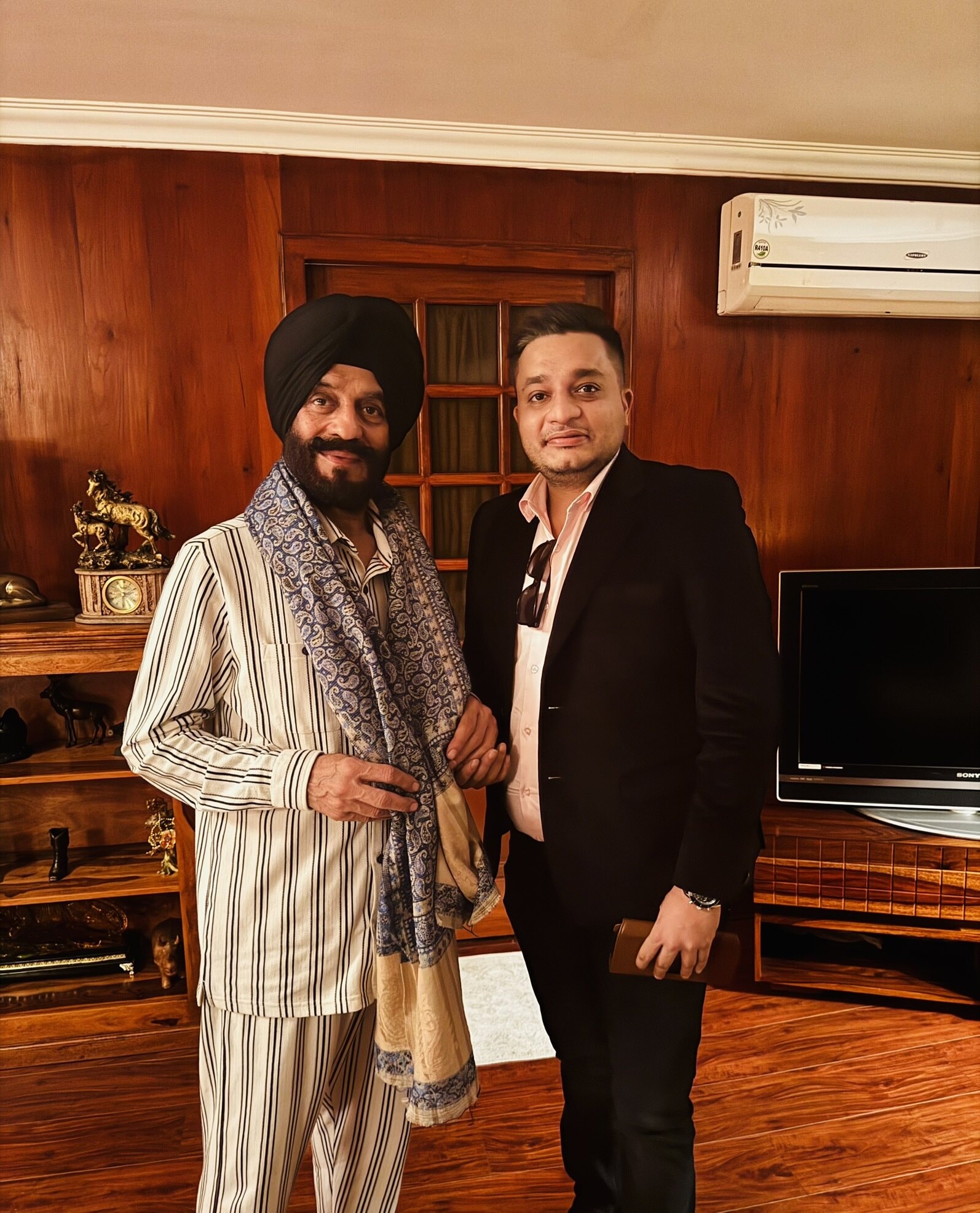 Nitish Jindal standing beside M. S. Bitta in a wood-paneled indoor room.