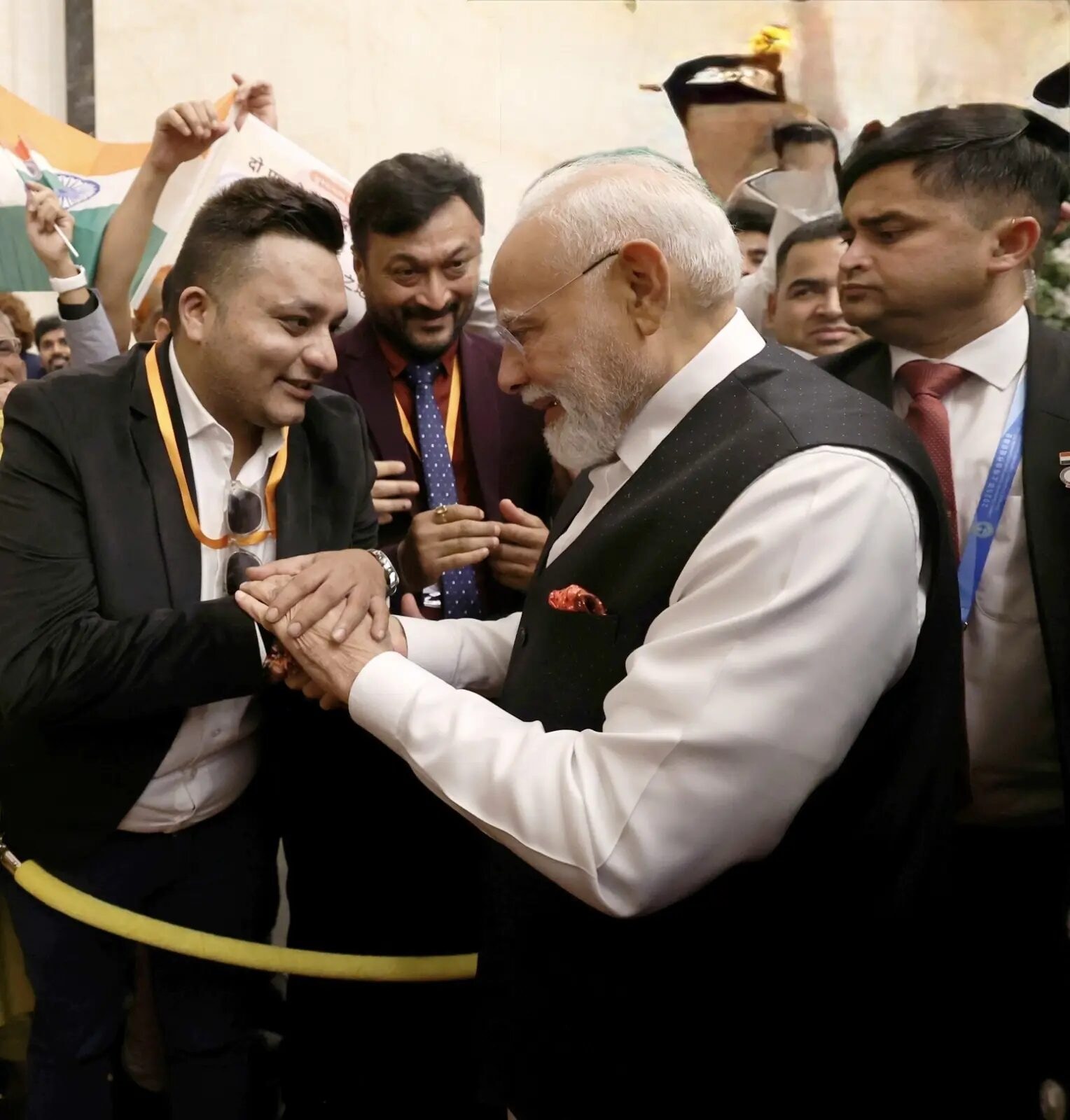 Nitish Jindal greeting Narendra Modi with joined hands amid a crowded public gathering.