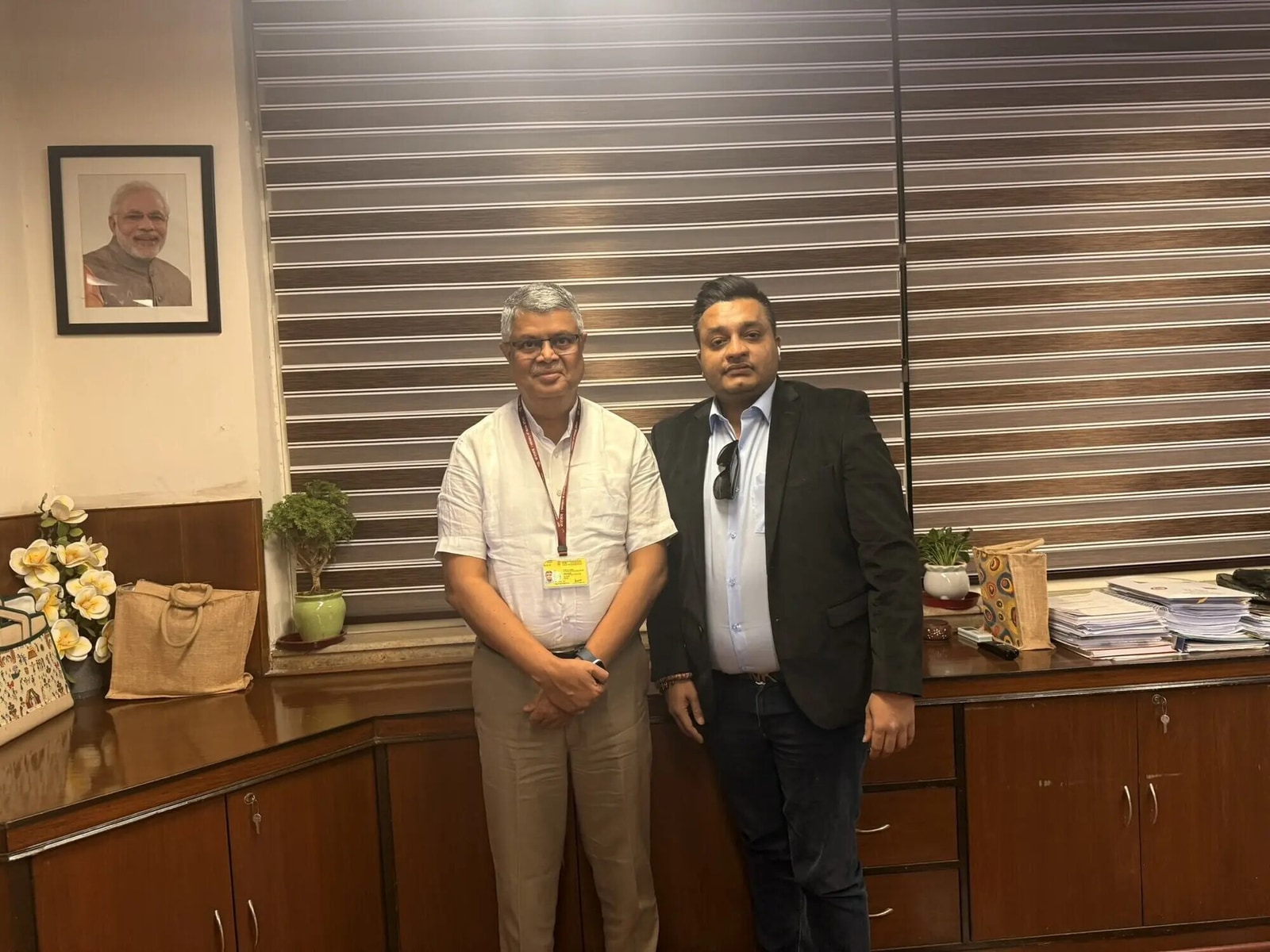Nitish Jindal standing beside an unnamed individual in a tidy indoor setting.