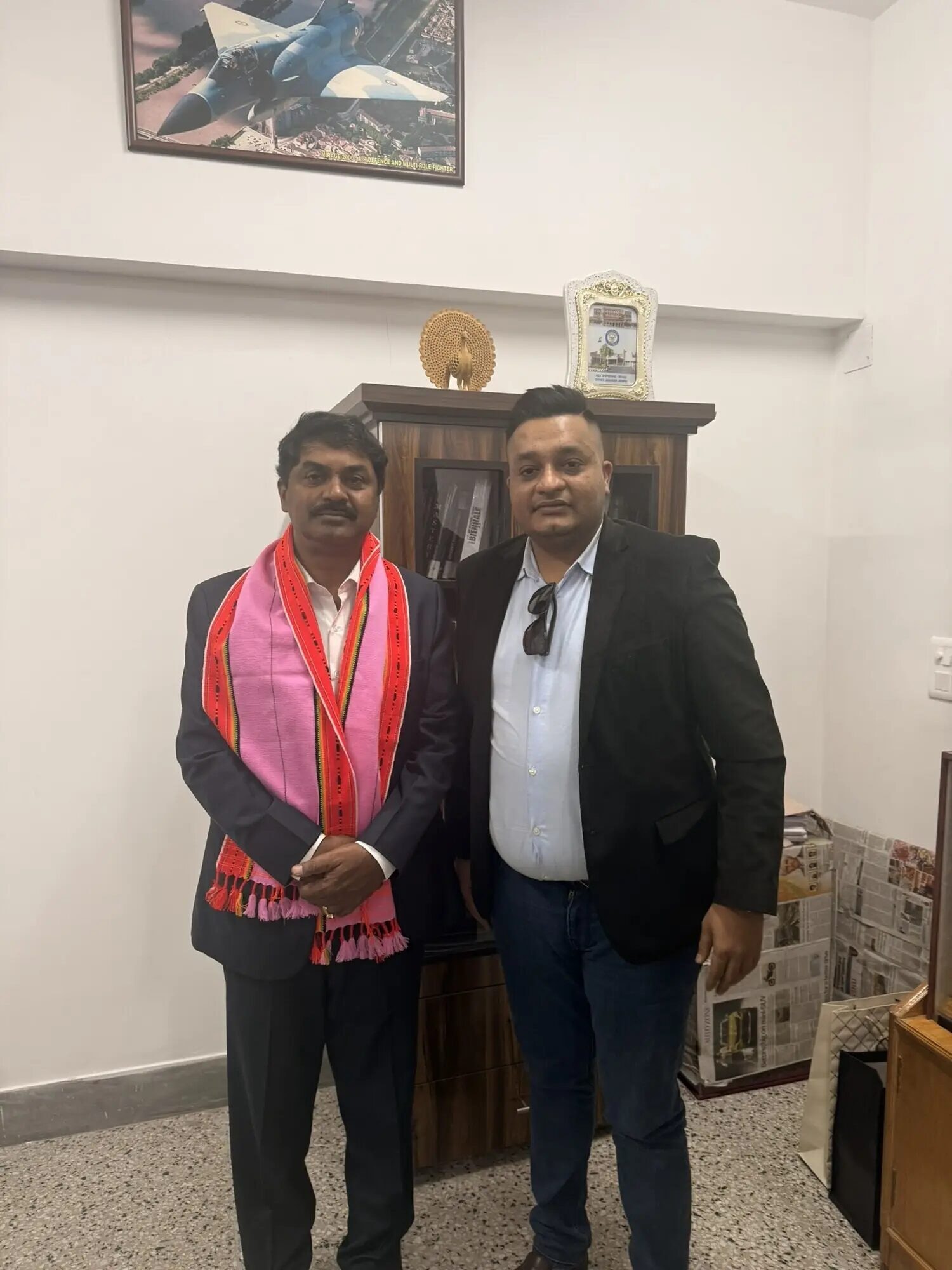 Nitish Jindal standing beside an unnamed individual wearing a bright patterned scarf.