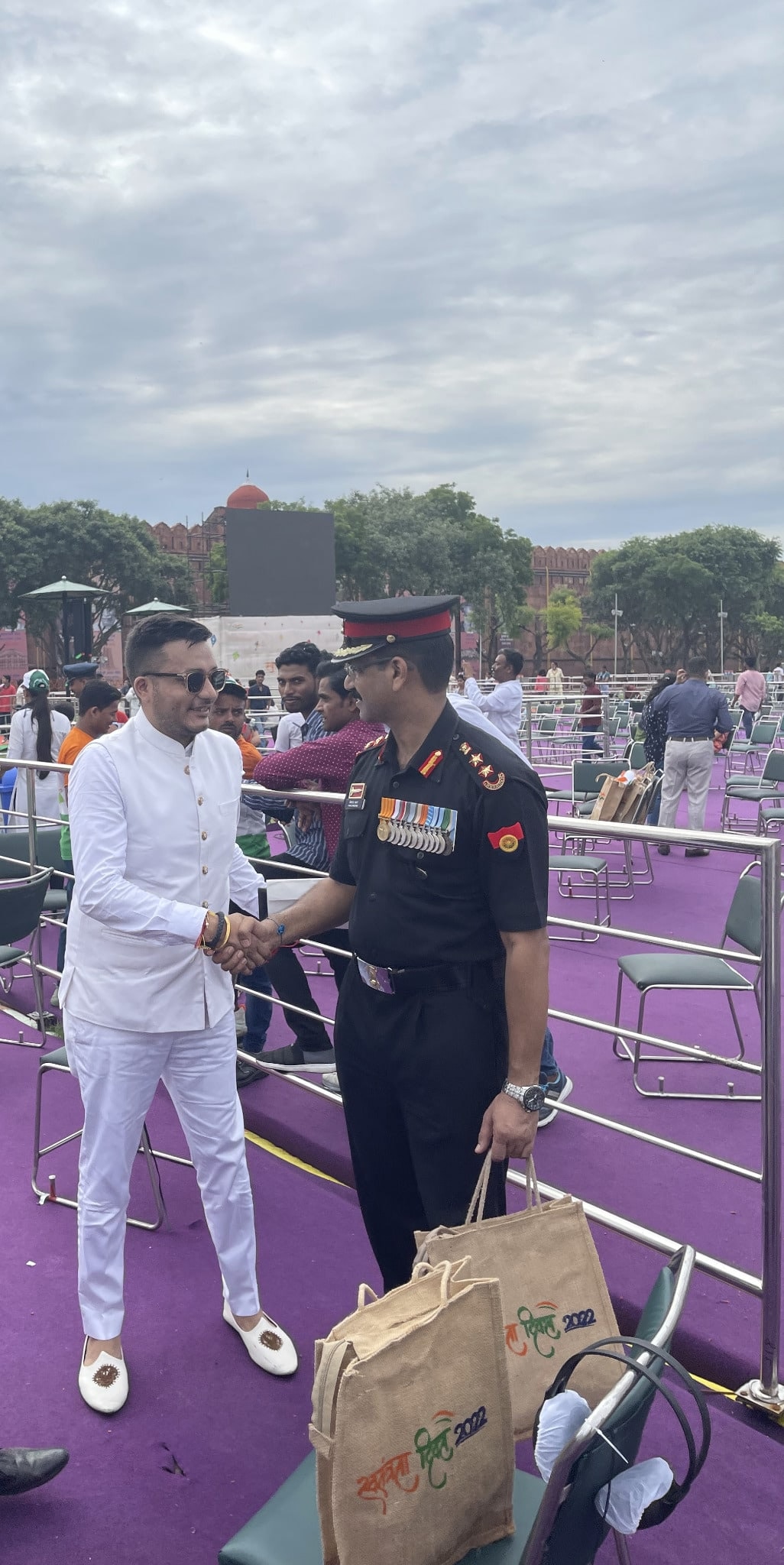 Nitish Jindal shaking hands with an unnamed individual wearing a dark ceremonial uniform.