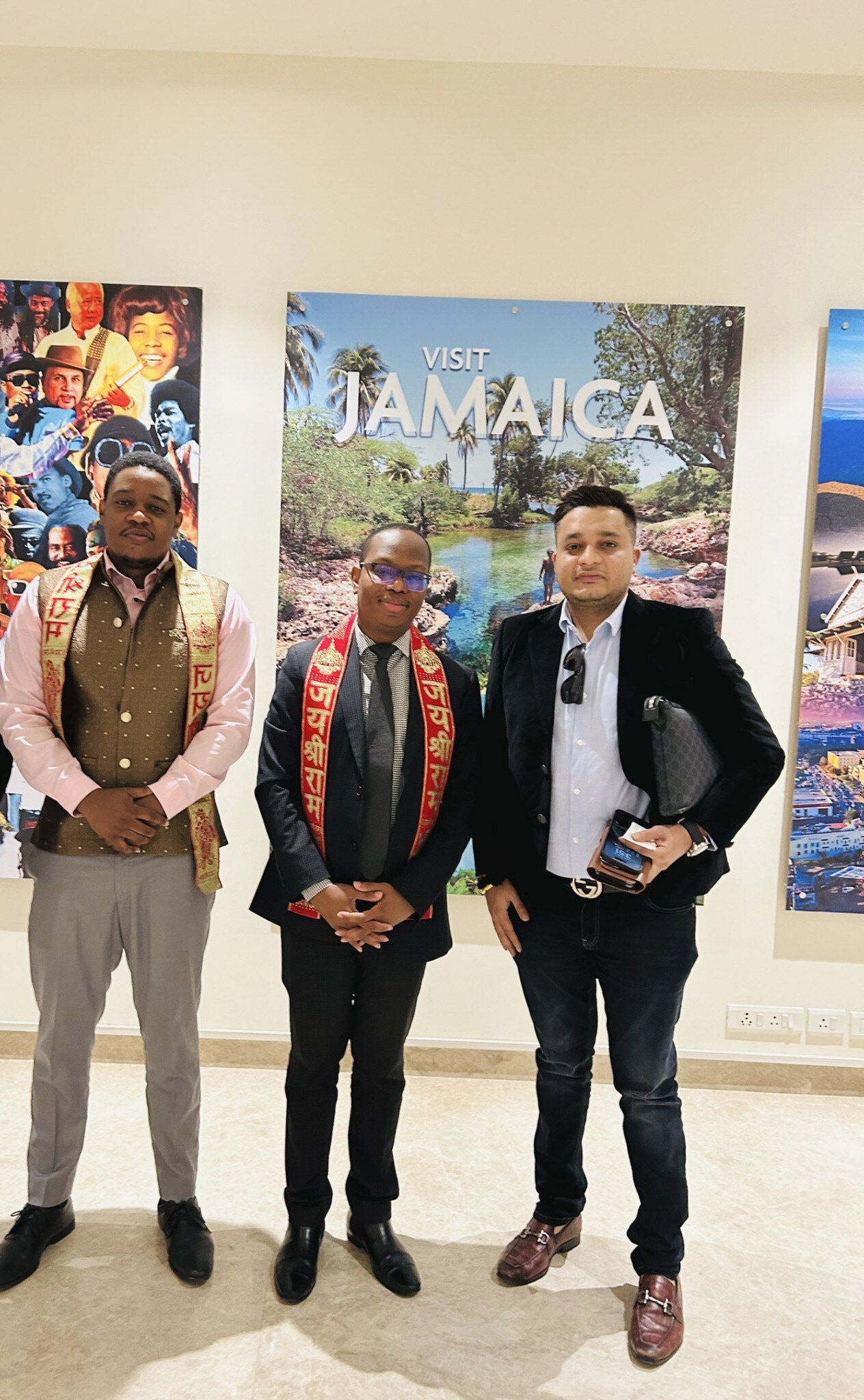 Nitish Jindal standing with two other men before a colorful travel-themed display.